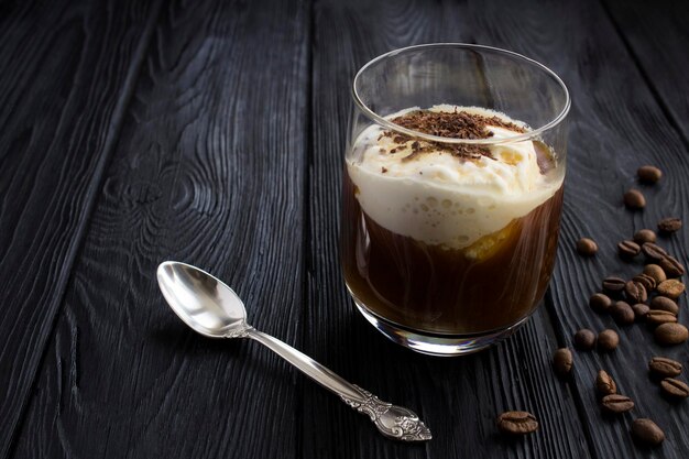 Café froid avec de la glace à la vanille dans le verre à boire sur le fond en bois noir. Fermer.