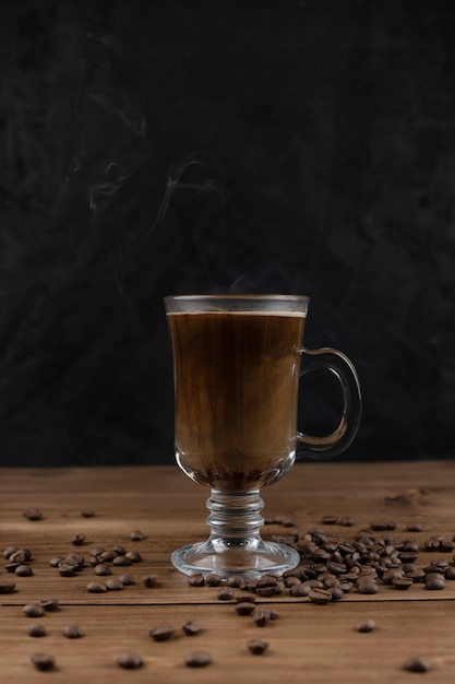 Café fumant sur une surface en bois et un fond noir.