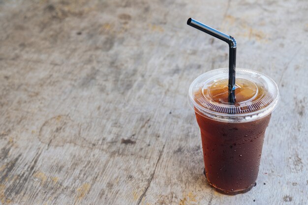 Café glacé americano noir sur le vieux bureau en bois