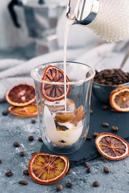 Café glacé au lait Boisson d'été Verser du lait dans un café avec un glaçon sur fond gris