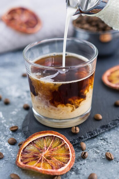 Café glacé au lait Boisson d'été Verser du lait dans un café avec un glaçon sur fond gris