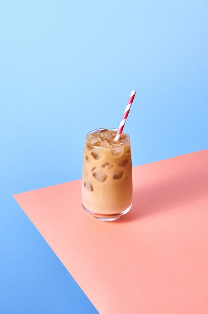 café glacé au lait en verre sur fond rose et bleu