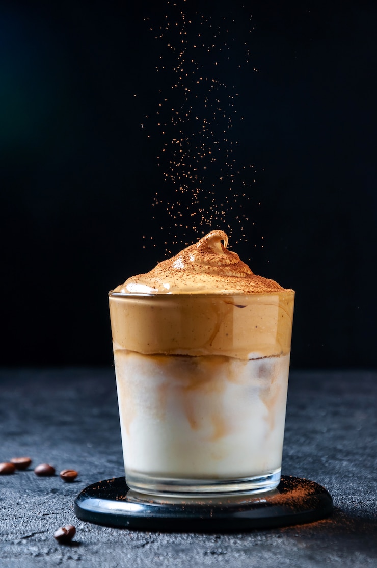 Photo café glacé dalgona et cacao tamisant. café fouetté crémeux à la mode. boisson d'été froide sud-coréenne
