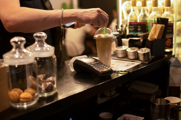 Café glacé dans un verre et un terminal de paiement. Petite entreprise mini café boisson à emporter.