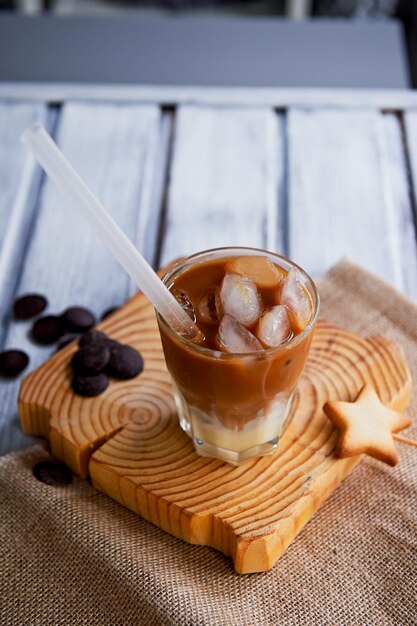 Le café glacé de Hong Kong dans un verre avec un fond en bois intéressant de paille