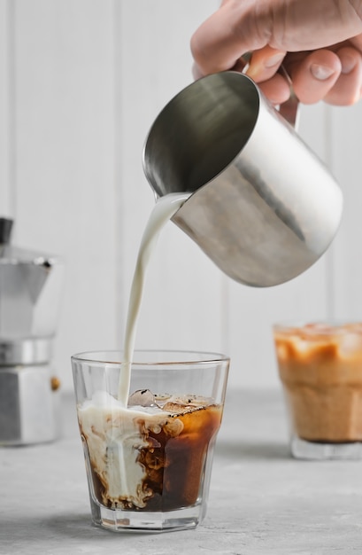 Café glacé sur une table en béton gris, versant la crème, mettant en valeur la texture et l'aspect rafraîchissant de la boisson