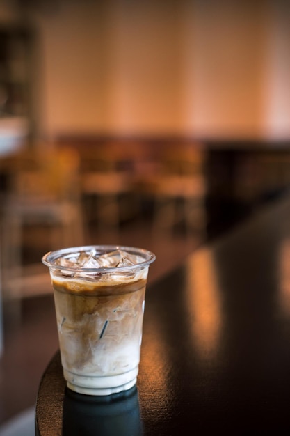 Café glacé sur une tasse en plastique avec de la crème qui y est versée montrant la texture