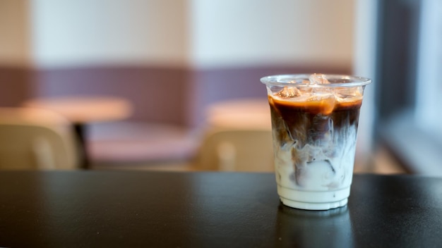 Café glacé sur une tasse en plastique avec de la crème qui y est versée montrant la texture