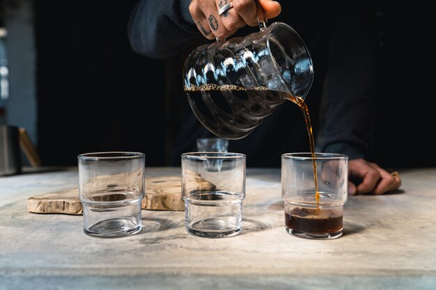 Café goutte à goutte, barista versant de l'eau sur du café moulu avec filtre, préparation du café