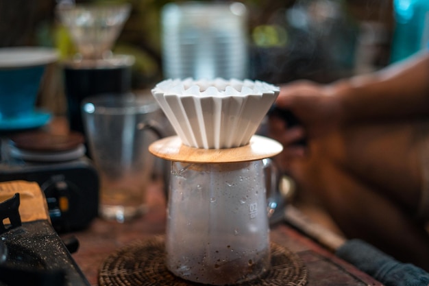 Café goutte à goutte barista versant de l'eau sur du café moulu avec filtre