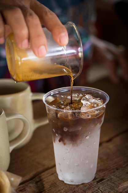 Café goutte à goutte dans un verre de glace en plastique transparent. café avec de la glace dans une glace en verre