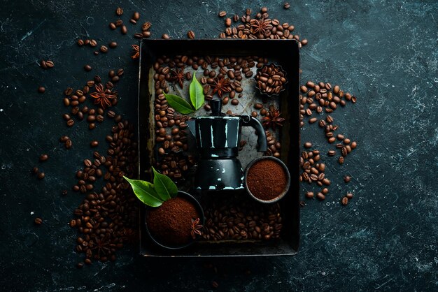 Café en grains de café parfumés torréfiés et cafetière sur fond de pierre noire Vue de dessus Espace libre pour votre texte
