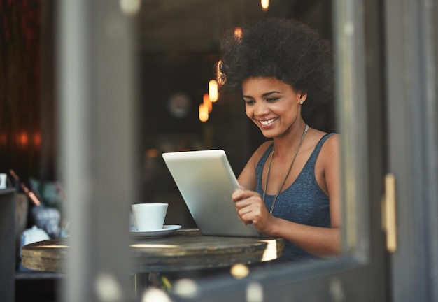 Café et un grand ebook Lifes good Photo d'une jeune femme à l'aide d'une tablette numérique dans un café