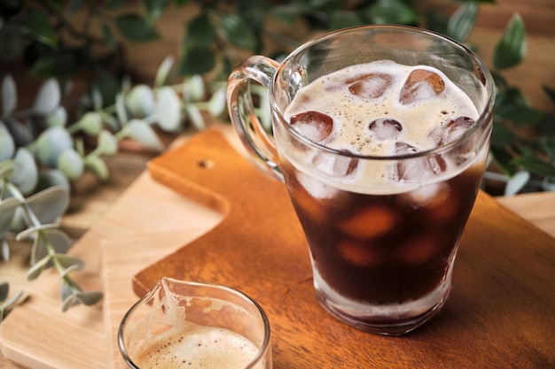 Café infusé noir glacé froid dans un verre avec des morceaux de glace sur une table en bois boisson fraîche d'été