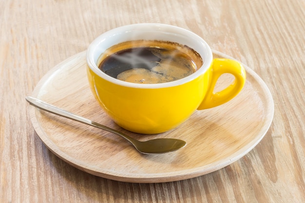 Café instantané dans la tasse jaune au-dessus de la plaque en bois