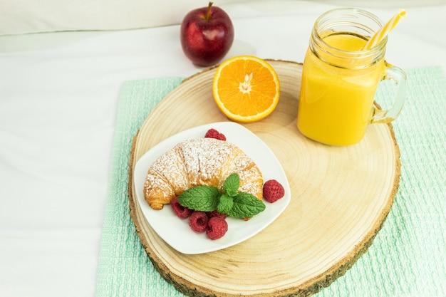 Café jus d'orange et un croissant sur une tige en bois