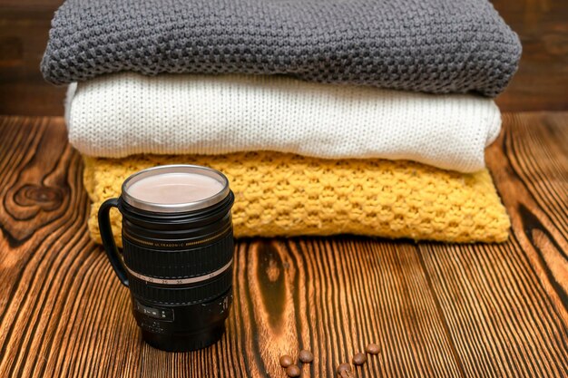 Café latte cacao au lait dans une tasse thermo, tasse à zoom sur fond en bois avec pulls chauds, boisson chaude par temps froid.