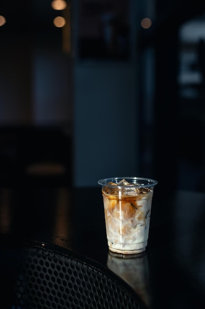 Café latte glacé dans un verre en plastique sur une table noire au café