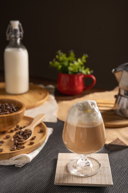 Café latte glacé servi avec garniture de crème fouettée et sirop de chocolat en verre à vin place sur table en bois