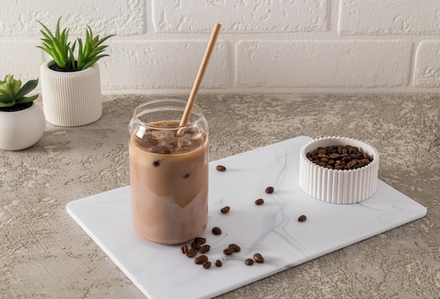 Café latte moka au lait dans un verre moderne sous forme de canette sur un plateau en marbre blanc et une table en béton une boisson tendance