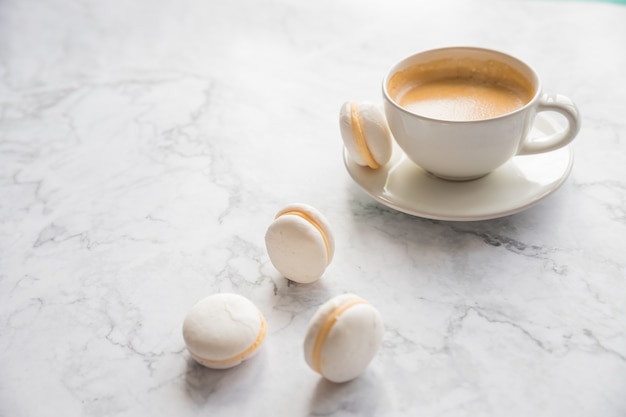 Café et macarons français sur fond de marbre.