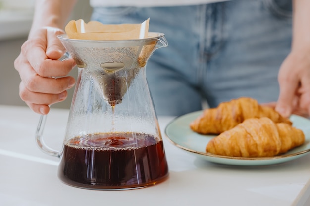 café le matin, une femme européenne prépare du café et le boit des croissants et du café pour le petit-déjeuner