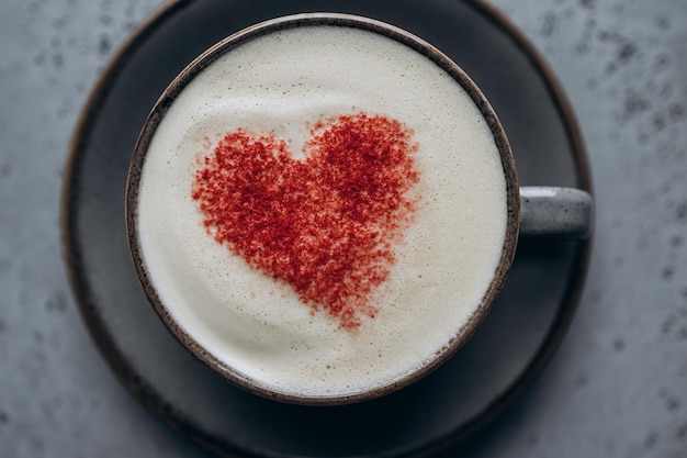 Photo café avec un motif en forme de coeur sur la mousse sur fond gris