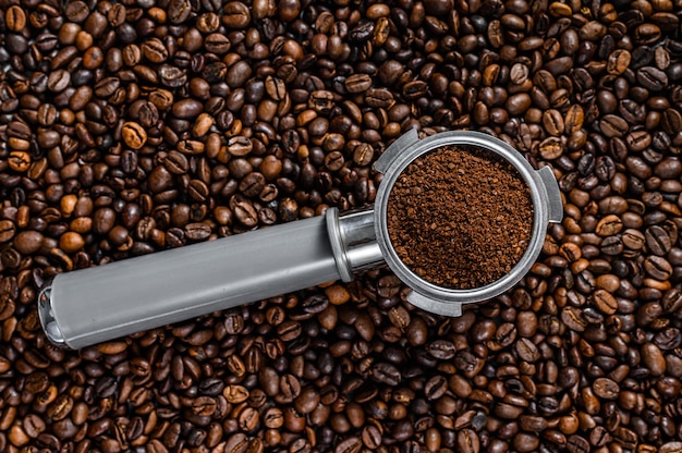 Café moulu dans le porte-filtre pour espresso avec des grains de café sur blanc. Vue de dessus.