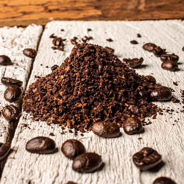 Café moulu et grains de café sur fond de bois blanc