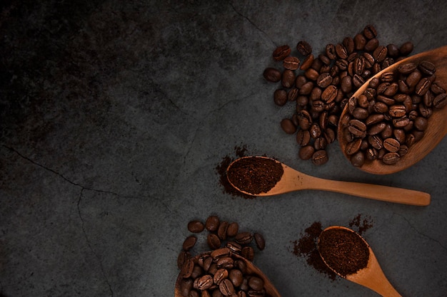 Café moulu et grains de café torréfiés dans des cuillères en bois sur fond sombre