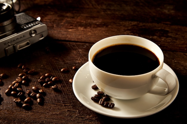 Le café noir chaud est sur le vieux bâton en bois avec un appareil photo