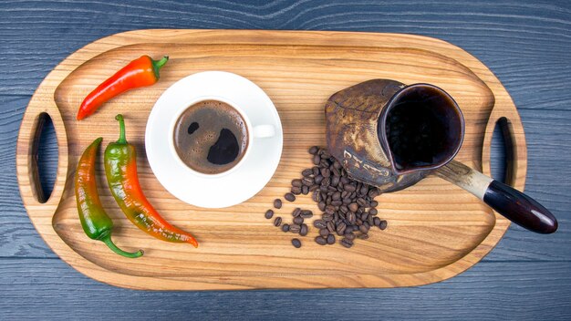 Café noir chaud fraîchement infusé dans une tasse blanche sur une planche de bois avec des grains de café piment et citron