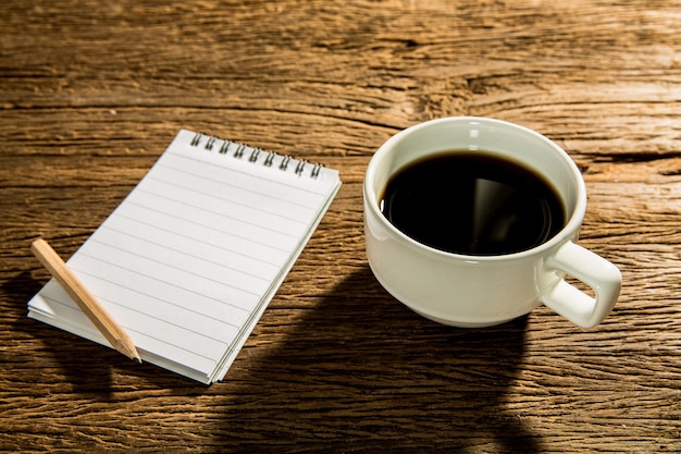 café noir chaud sur table de travail en bois et carnet de notes