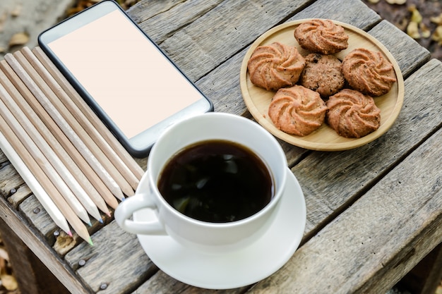 Café noir et cookie sur la table en bois