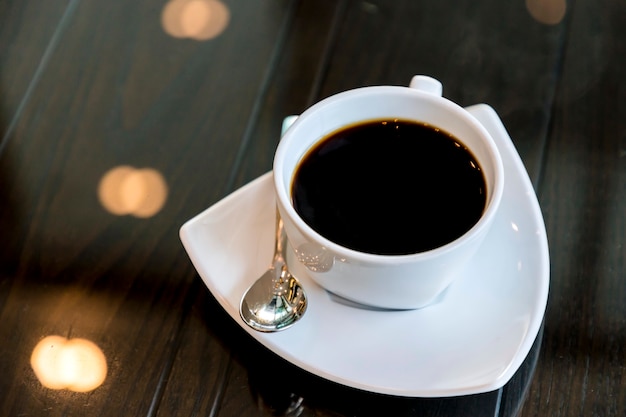 Café noir dans une tasse blanche sur une table en verre.