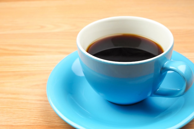 Café noir dans une tasse bleue sur fond de table en bois marron