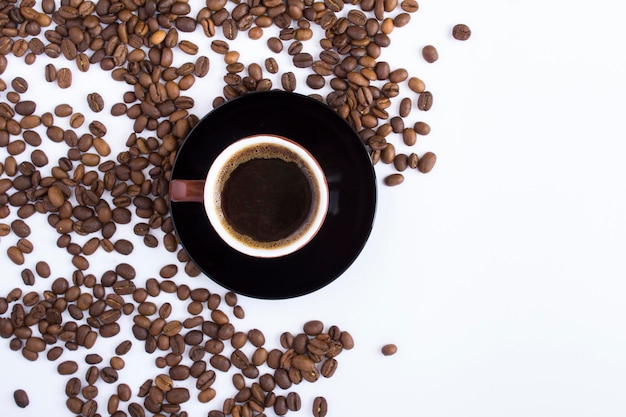 Café noir dans la tasse brune et grain de café torréfié sur fond blanc Vue de dessus Espace de copie