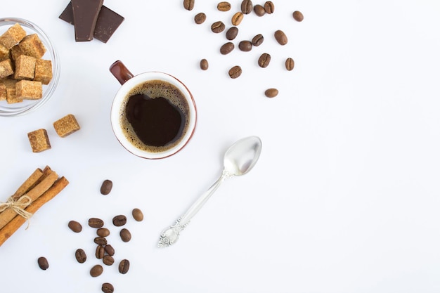 Café noir dans la tasse brune de sucre en grains de café et de cannelle sur fond blanc Vue de dessus Espace de copie