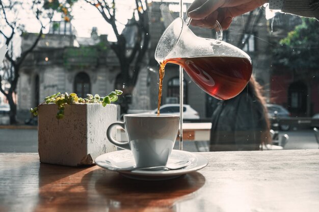 Café noir dans une tasse à café en porcelaine blanche sur une table en bois devant un vitrail