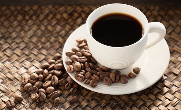 Café noir dans la tasse, espresso et grain de café sur une assiette, la caféine aide à être énergique