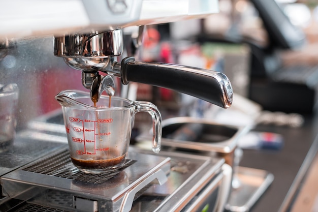 café noir dans une tasse à mesurer mis sur une cafetière