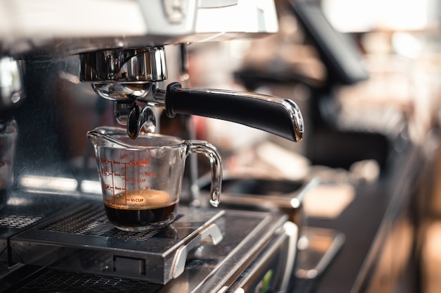 café noir dans une tasse à mesurer mis sur une cafetière