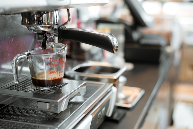 café noir dans une tasse à mesurer mis sur une cafetière