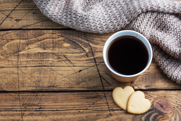 Café noir dans une tasse en papier et biscuits en forme de cœur