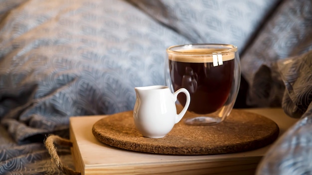 Café noir dans une tasse transparente au lit le matin d'automne