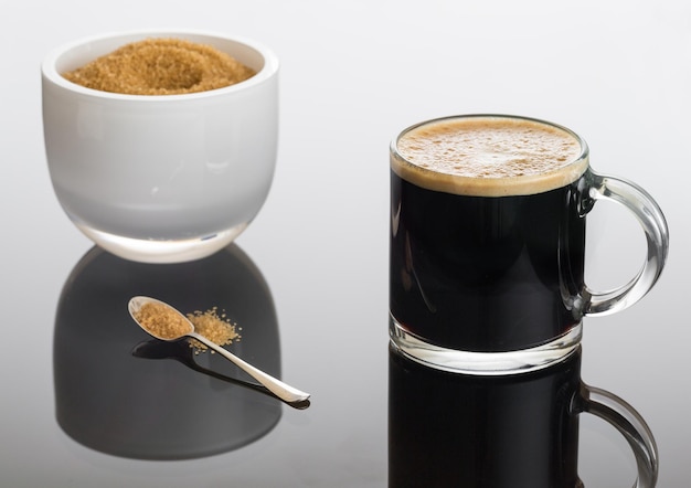 Café noir et mousse dans une tasse en verre avec du sucre