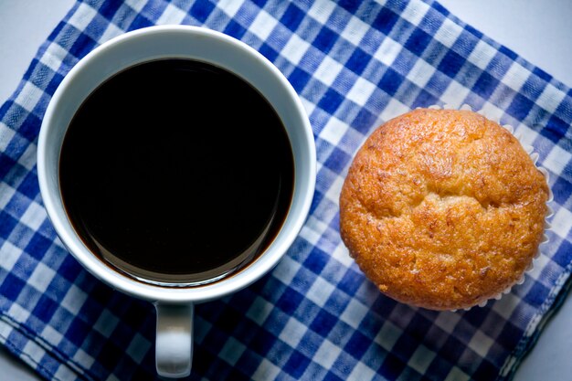 Café noir en verre blanc et gâteau aux bananes sur tissu.