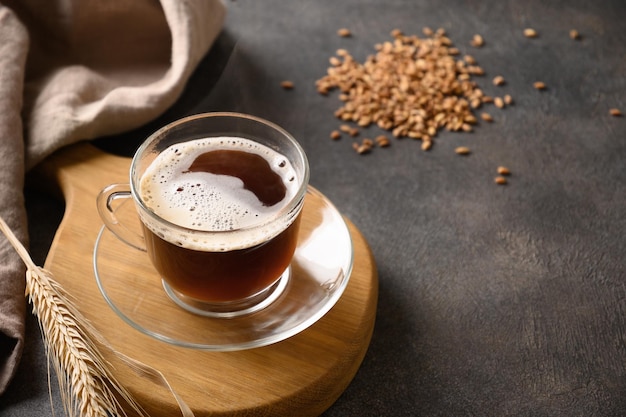 Café d'orge dans une tasse blanche et épis d'orge sur fond marron