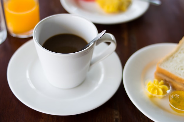 Café et petit déjeuner mis sur la table en bois