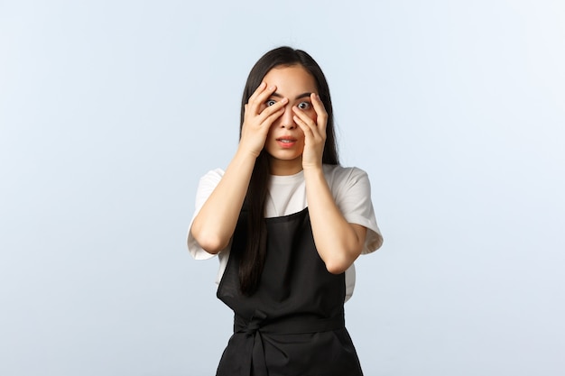 Café, petite entreprise et concept de démarrage. Employée effrayée et embarrassée qui regarde quelque chose de terrible, couvre les yeux, regarde avec les doigts une scène choquante